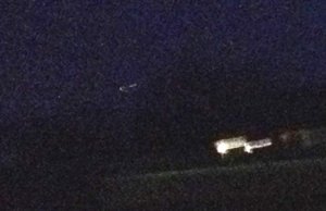 I had to lighten the photo and zoom and crop to get it to show up close. It's the thin string of light. The bright lights below to the right are house lights.